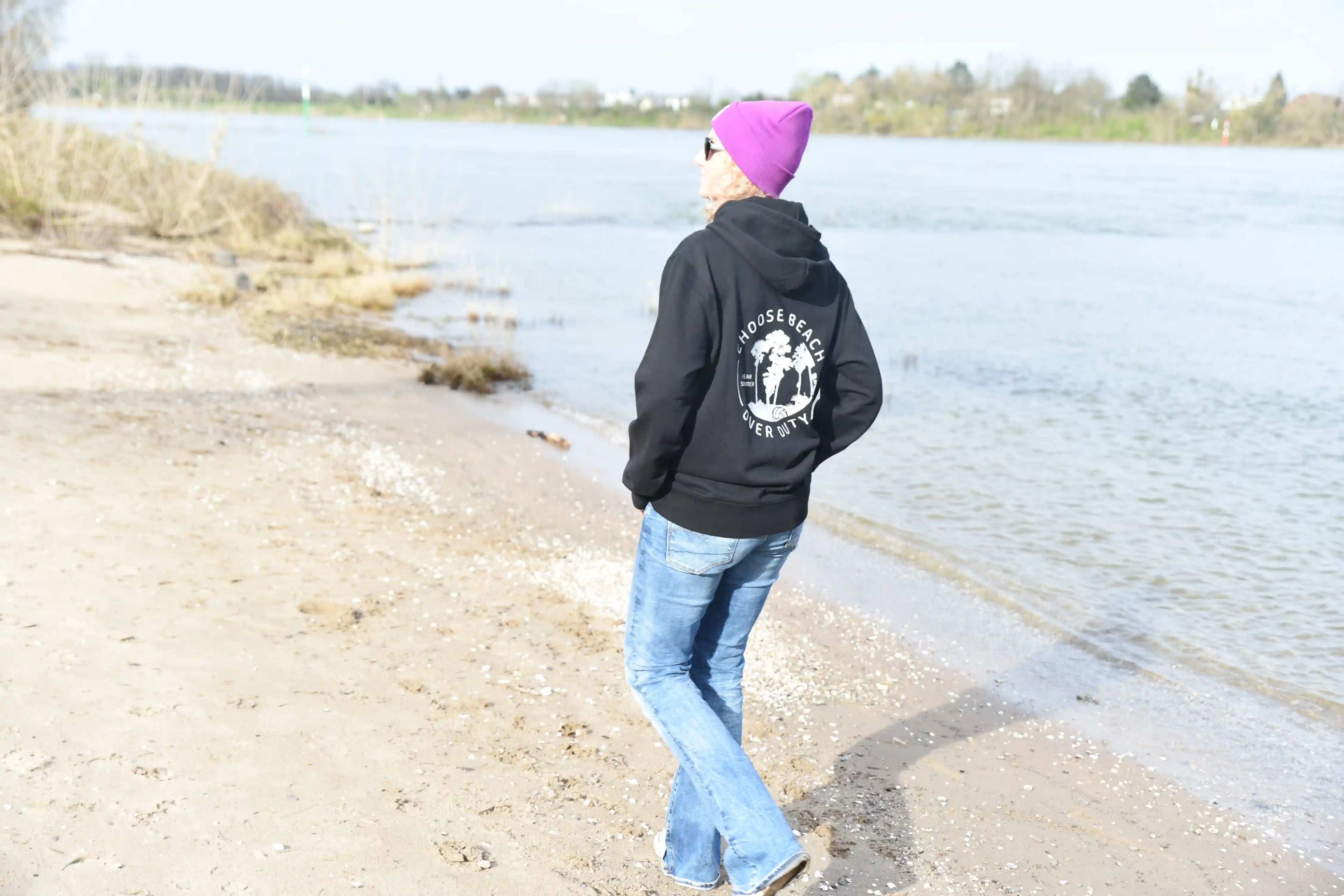 Beachvolleyball Bekleidung Streetwear Sportswear Oberteil hoodie black mit Markenlabel
Großer Rückenprint Palmen neon gelb wear summer Frau am Strand mit lila farbener Beanie Sonnenbrille 